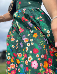 Close-up of a person wearing a green dress with colourful floral pattern. Devoi clothing