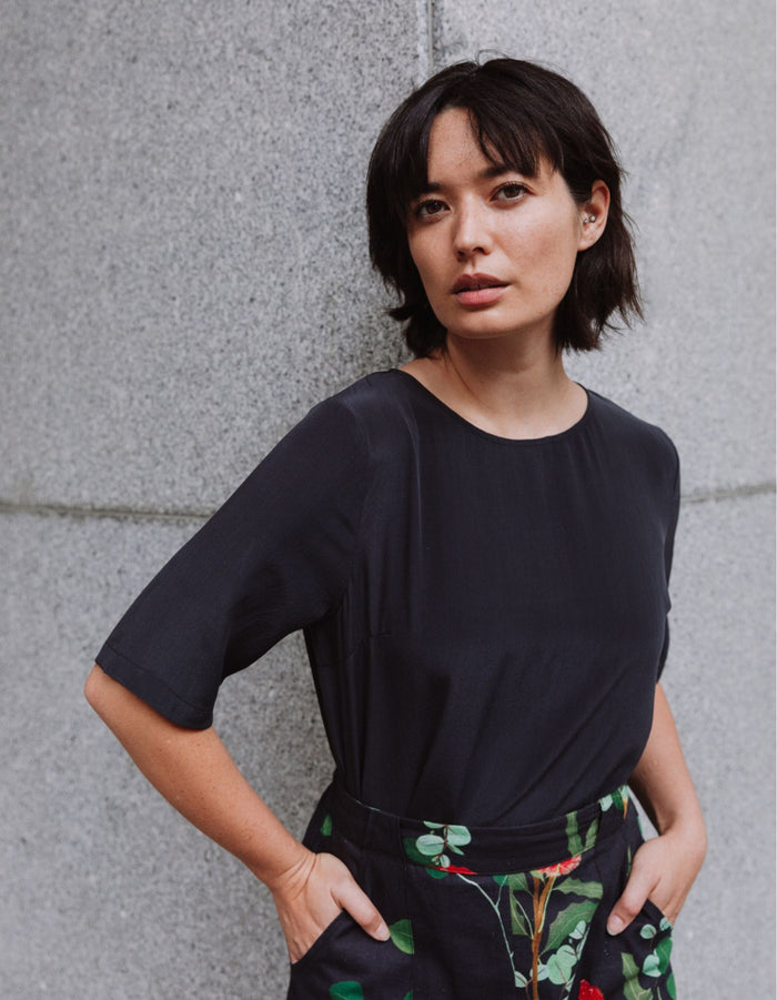 Model wearing a DEVOI black Lise top in plain black silk crepe. Front close up view