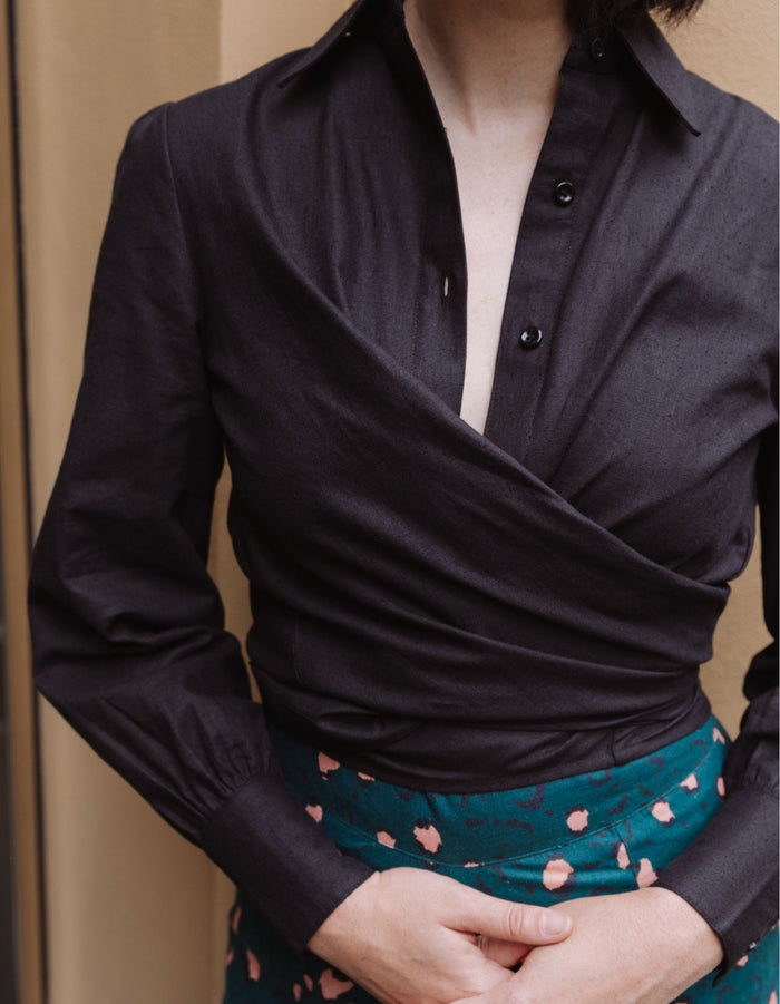 Woman wearing a black DEVOI Susie shirt in linen with a long wrap tie at the waist. Close-up front view