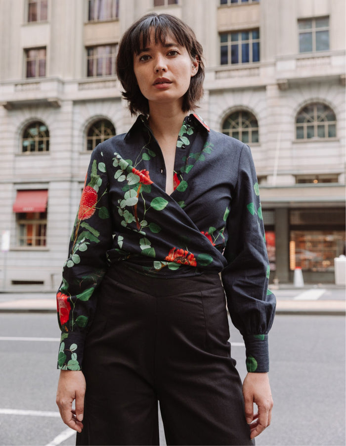 Model wearing the DEVOI Susie Shirt in black Wild Blooms floral printed linen, with waist ties and long cuffs. Front