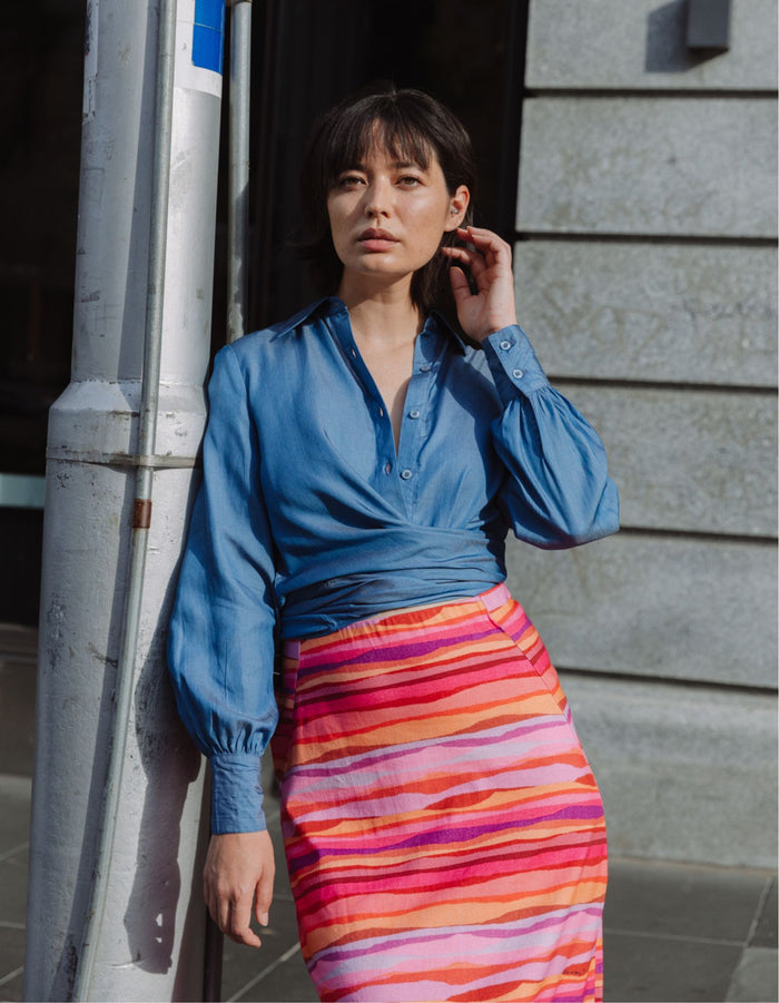 Model wearing the DEVOI Susie Shirt in soft blue Tencel denim with waist ties and long cuffs. Front view close-up.