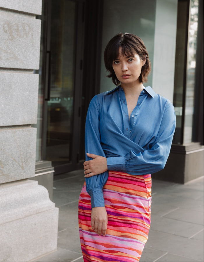 Model wearing the DEVOI Susie Shirt in soft blue Tencel denim with waist ties and long cuffs. Front view on model.