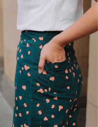 Person wearing a green skirt with pink leopard printed pattern and white top.