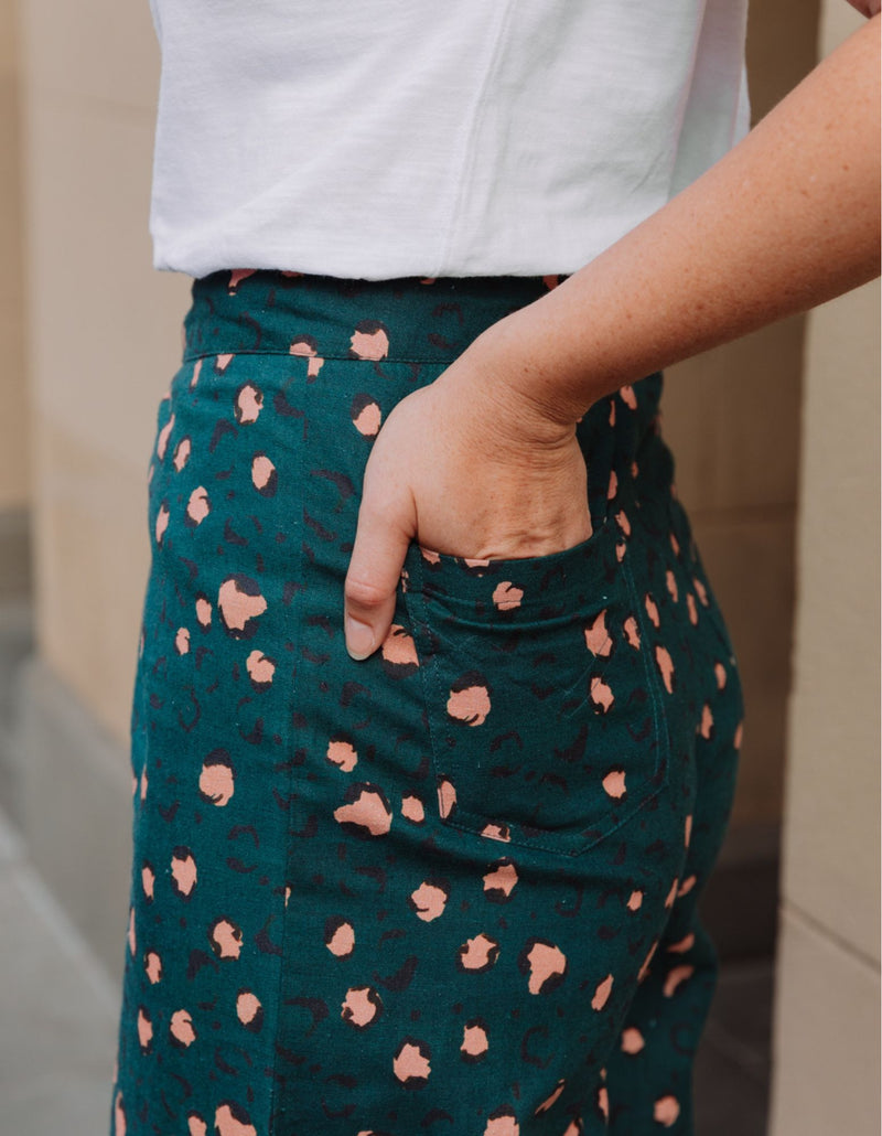 Person wearing a green skirt with pink leopard printed pattern and white top.
