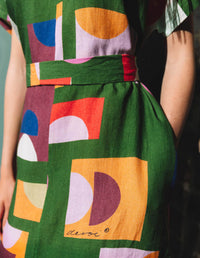 DEVOI green Ivy dress in our Olive Just Pretend print. 100% Linen. Dress has a v-neck, short sleeves and a front and back centre seam. The dress comes with a belt in self fabric to tie at the waist. Front close-up