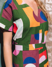 DEVOI green Ivy dress in our Olive Just Pretend print. 100% Linen. Dress has a v-neck, short sleeves and a front and back centre seam. The dress comes with a belt in self fabric to tie at the waist. Front bodice close-up view