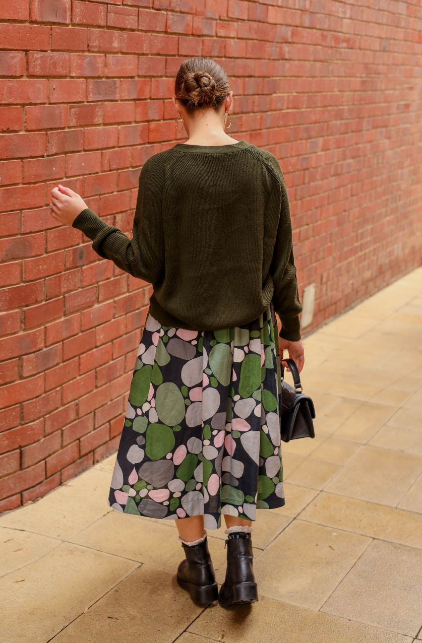 Printed linen skirt in a green pebbles print. Midi length with pocket and an elasticated waistband. Back view