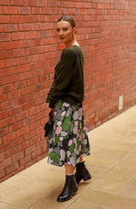 Printed linen skirt in a green pebbles print. Midi length with pocket and an elasticated waistband. Side view