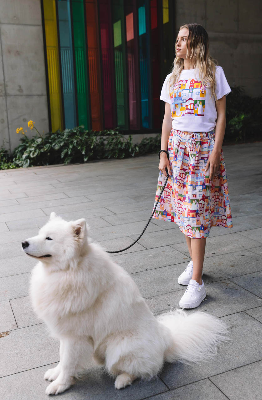     DA_278_Devoi_200311  1000 × 1500px  DEVOI Kathleen skirt in Urban Scapes print. Front view with a white puppy. 100% Linen, hand painted print.