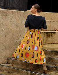 DEVOI Kathleen skirt in new print Mustard Sauros. Elastic waist and pockets. Skirt falls just below the knee. Drawstring tie at front waist. Back view.