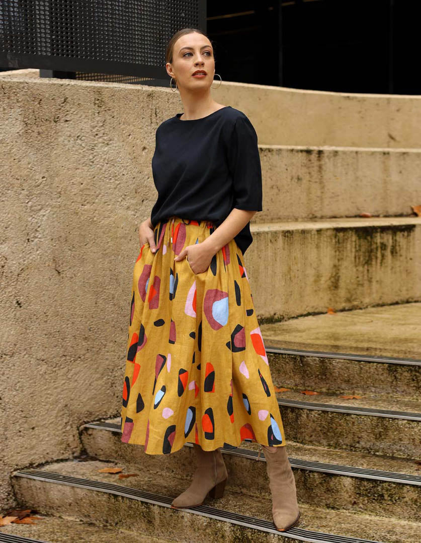 DEVOI Kathleen skirt in new print Mustard Sauros. Elastic waist and pockets. Skirt falls just below the knee. Drawstring tie at front waist. Front view.