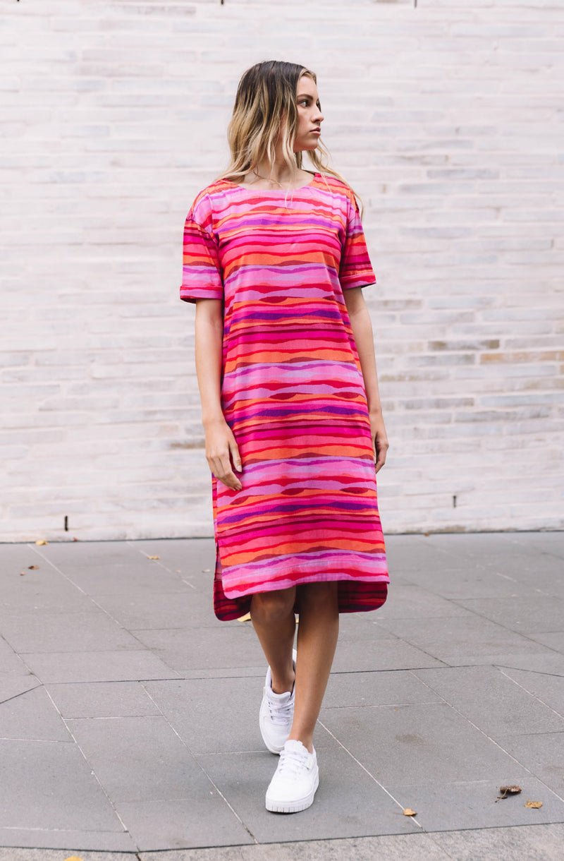DEVOI Madeleine dress in Sunset tide print. 100% Organic cotton jersey. pink hand painted print. Designed in melbourne. Short sleeves and side pockets.  Front view on model
