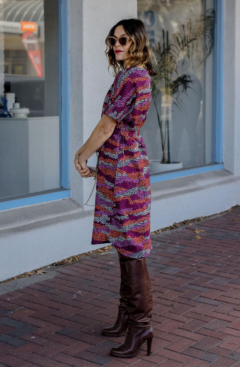 DEVOI Annie dress with a round neckline in Black Sediment print. Black, pink orange and plum colours. Shift dress with a tie belt at the waist. The dress has pockets. Side view