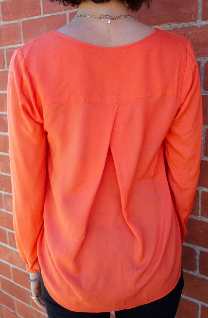 DEVOI Everleigh top blouse in bright orange. Our Everleigh is loose fitting long sleeved top with a folded cross over detail at the front, and flattering v-neckline, full length sleeves and elasticated cuffs. The back has an elegant fold below the yoke panel.