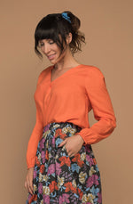 DEVOI Everleigh top blouse in bright orange. Our Everleigh is loose fitting long sleeved top with a folded cross over detail at the front, and flattering v-neckline, full length sleeves and elasticated cuffs. The back has an elegant fold below the yoke panel.