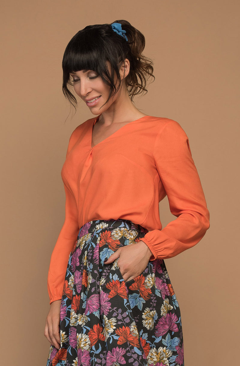 DEVOI Everleigh top blouse in bright orange. Our Everleigh is loose fitting long sleeved top with a folded cross over detail at the front, and flattering v-neckline, full length sleeves and elasticated cuffs. The back has an elegant fold below the yoke panel.