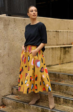 DEVOI Kathleen skirt in new print Mustard Sauros. Elastic waist and pockets. Skirt falls just below the knee. Drawstring tie at front waist. Front view.