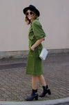 DEVOI Maya skirt in moss green colour. A-line shape with metal zip detail down the front of the skirt with a split at the front hem. Front and back pockets. Back waistband is elasticated. side view