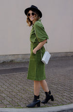 DEVOI Maya skirt in moss green colour. A-line shape with metal zip detail down the front of the skirt with a split at the front hem. Front and back pockets. Back waistband is elasticated. side view